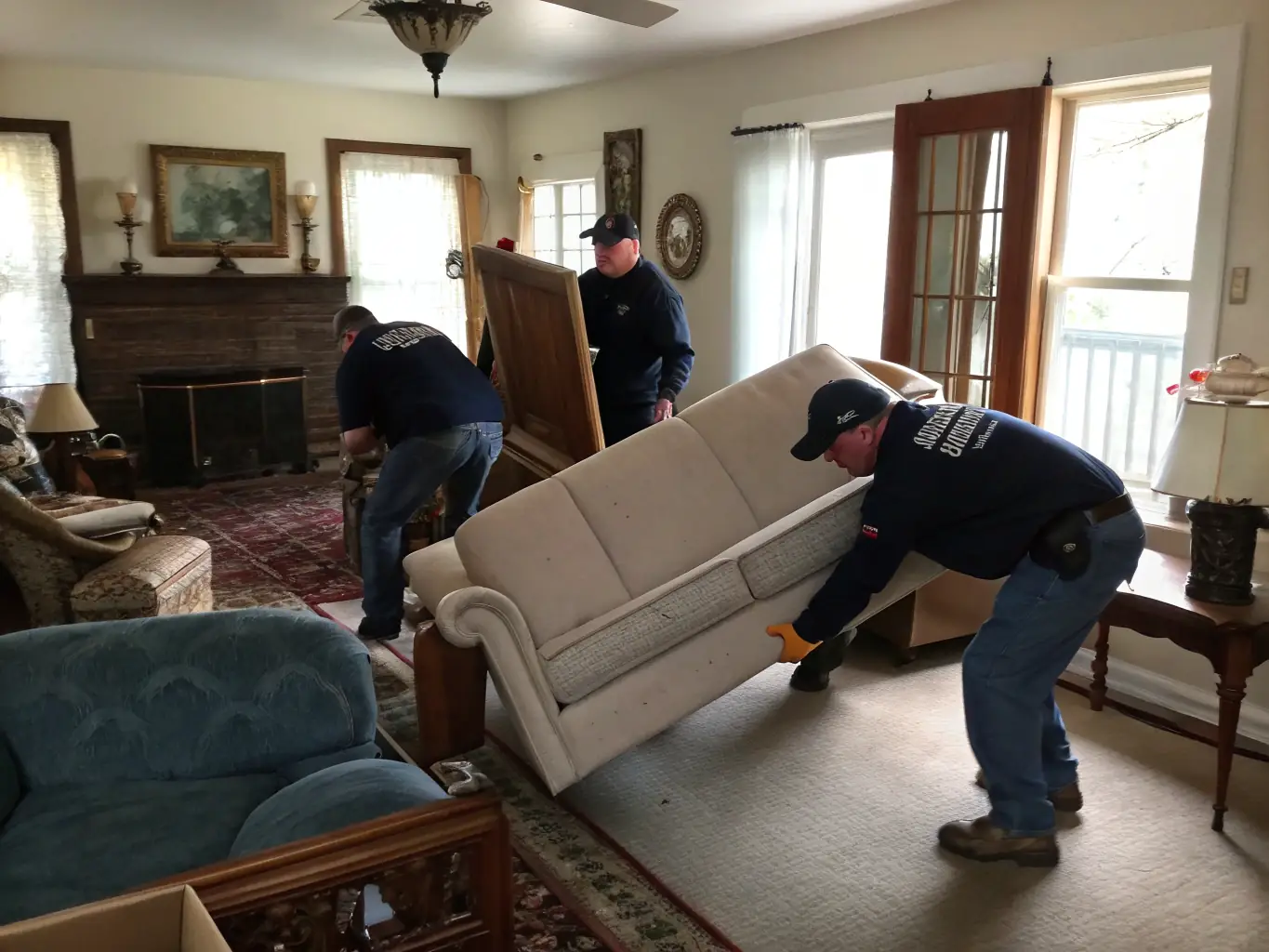 A team of movers carefully transporting a sofa into a new home, illustrating ReadySet Help's furniture moving service.